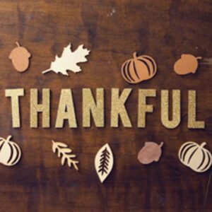 thankful in wood letters with small fall decorative decals: leaves, pumpkins, and acorns.